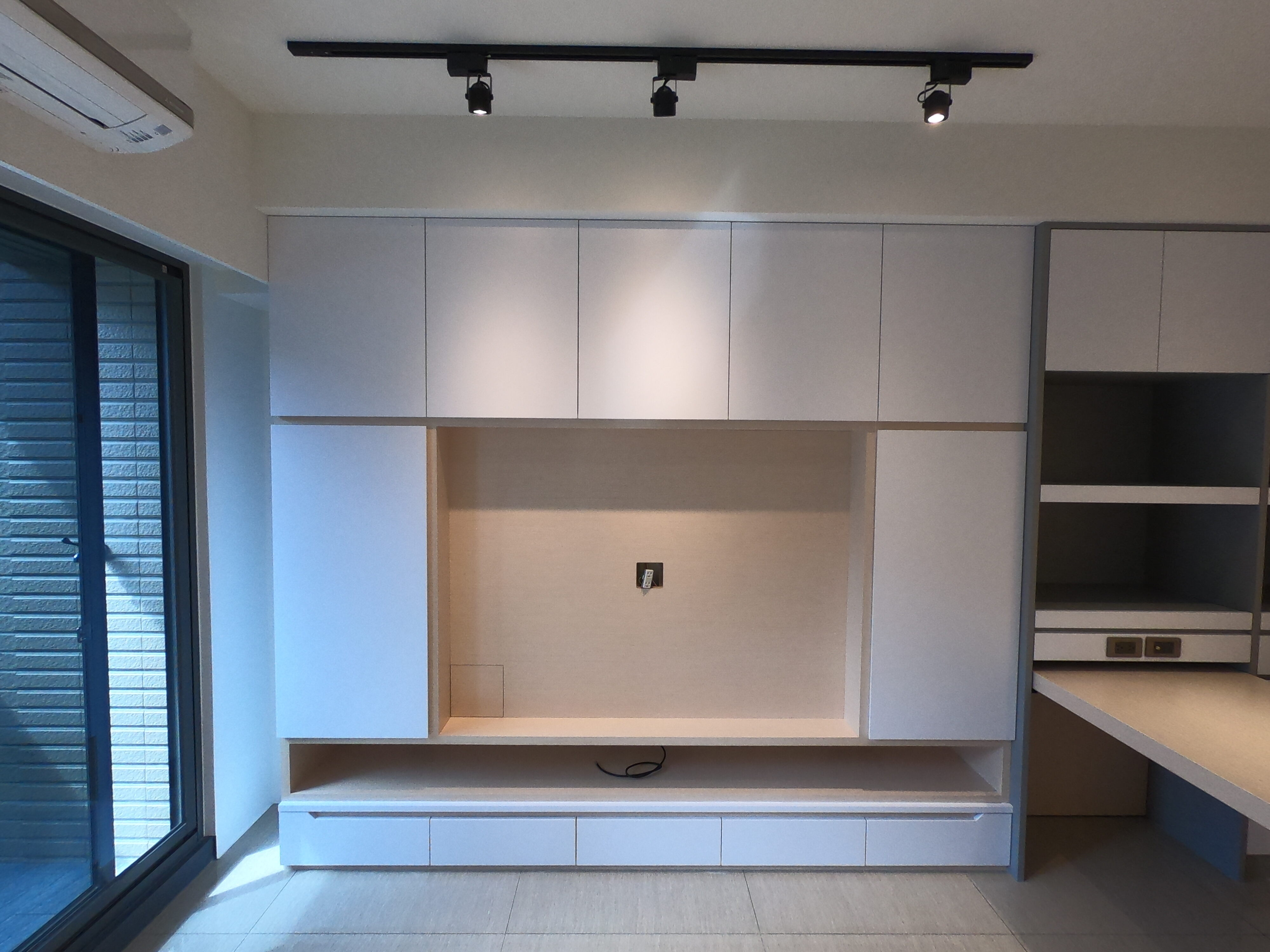 打造現代簡約風格，融合嵌入式電視牆、上掀式收納櫃與多功能工作桌，提升空間利用率。搭配高櫃與開放式層架，滿足收納需求，同時維持空間的整潔與美感。