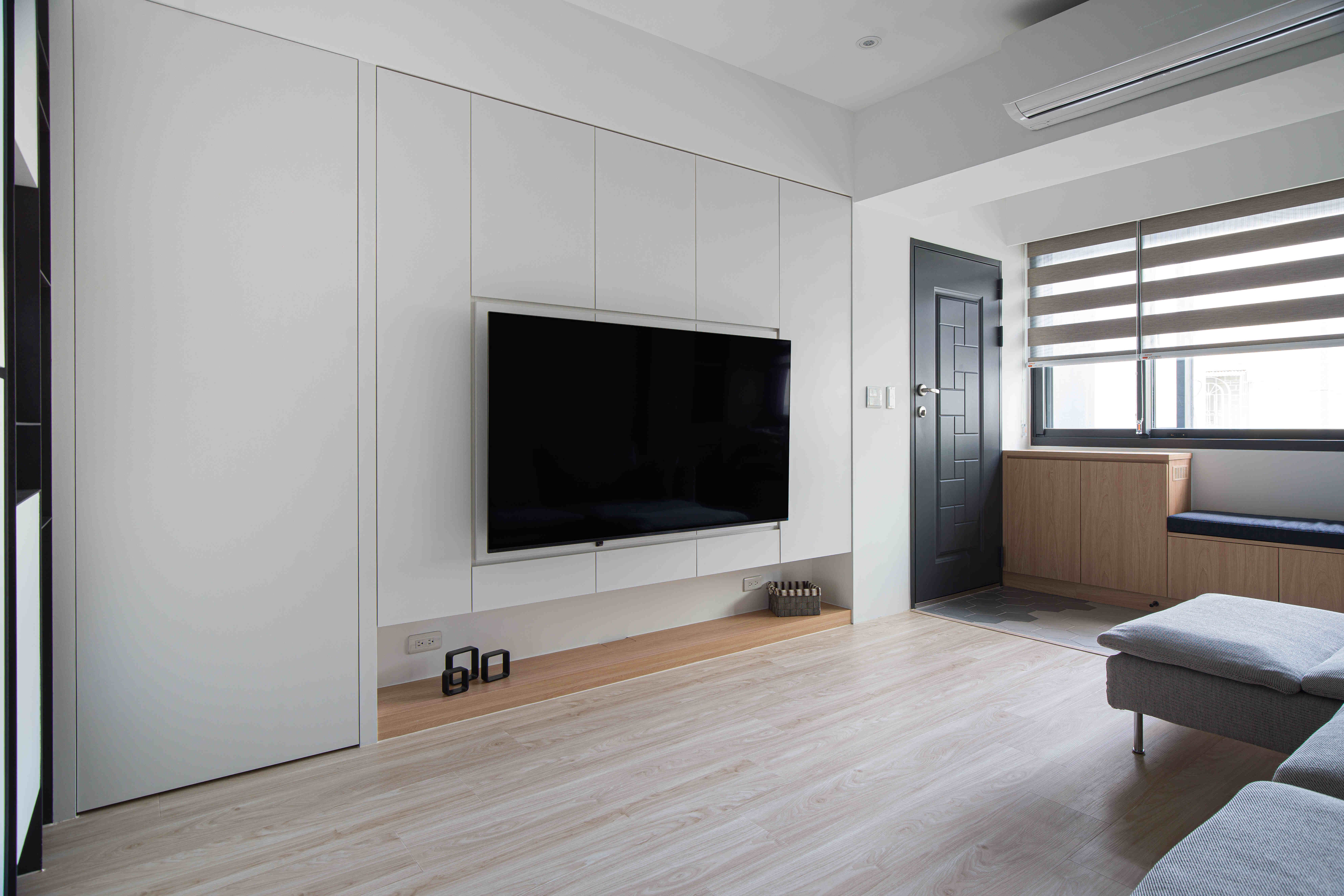 本案採用現代簡約設計，透過灰色調牆面與木質元素的搭配，打造沉穩而溫暖的客廳氛圍。L型布沙發提供舒適的休憩區域，搭配懸掛式壁燈，增添層次感與設計感。開放式空間串聯客廳、書房與餐廳，使動線更為流暢，同時透過異材質拼接設計，讓空間更具現代感。適合追求極簡風格、簡約居家裝潢的屋主，展現獨特品味。